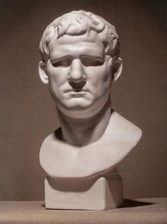 a white marble bust of a man's head with his eyes closed and one eye partially open