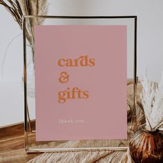 a pink card and gift box sitting on top of a table next to a vase