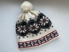 a white and black knitted hat with a pom - pom