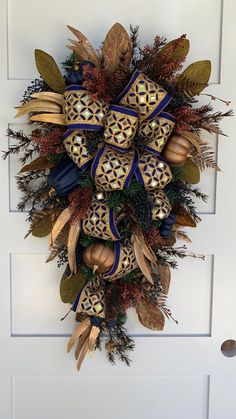 a wreath on the front door decorated with gold, blue and green decorations for christmas