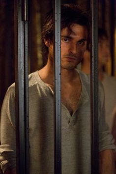 a man is standing behind bars in a jail cell