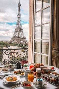 the table is set with food and drinks in front of the eiffel tower