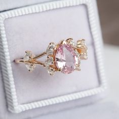 a pink diamond ring sitting on top of a white box