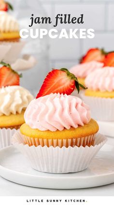 strawberry cupcakes with white frosting and strawberries on top, sitting on a plate