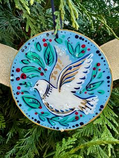 an ornament hanging from a christmas tree decorated with blue and gold designs, featuring a dove