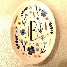 a decorative plate with the letter b painted on it's side and floral designs