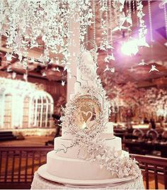 a white wedding cake with butterflies hanging from the ceiling