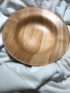 a wooden bowl sitting on top of a white blanket