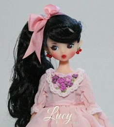 a doll with long black hair wearing a pink dress