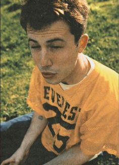 a young man sitting in the grass with his eyes closed