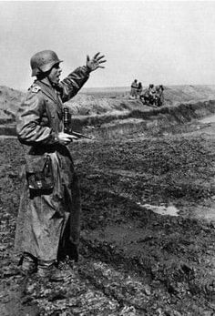 an old black and white photo of a man in trench coat talking to another man