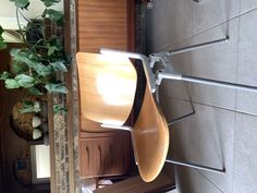 a wooden chair hanging from the side of a wall next to a potted plant