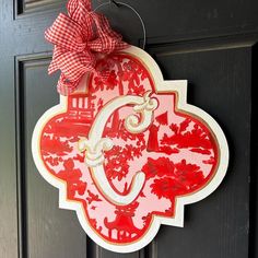 a red and white door hanger with a bow on it's front door