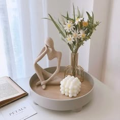 a vase with flowers in it sitting on a table next to a figurine