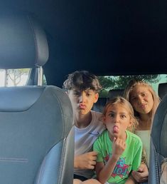 three children sitting in the back seat of a car