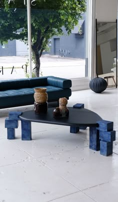 a blue couch sitting next to a coffee table on top of a white tiled floor