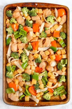 a casserole dish with chicken, broccoli, carrots and onions