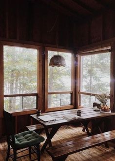 a table and bench in a room with large windows