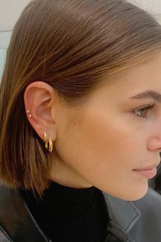 a close up of a person wearing earrings and looking at something in the distance