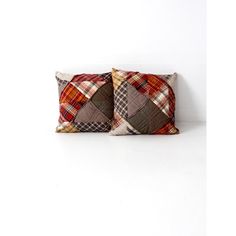 two brown and red plaid pillows sitting next to each other on a white surface,