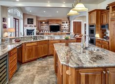 a large kitchen with marble counter tops and wooden cabinets