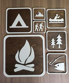 four square stickers with different symbols on them, including a canoe, kayak and campfire