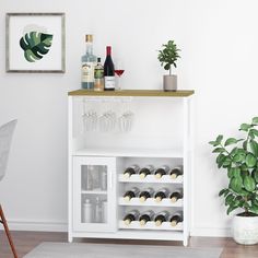 a white bar cart with wine glasses and bottles on it in front of a potted plant