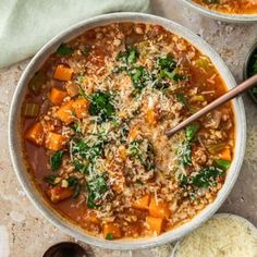 two bowls filled with soup and rice on top of a white counter next to spoons