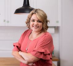 a woman standing in a kitchen with her arms crossed