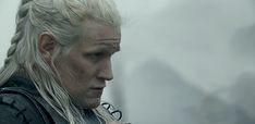 a man with white hair and braids looks at something