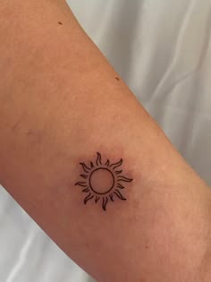 a small tattoo on the arm of a person with a sun in the middle,