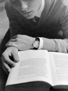 a young man reading a book while wearing a watch