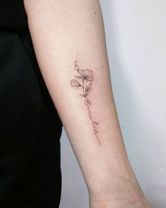 a woman's arm with a small flower tattoo on the left side of her arm