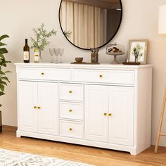 a white dresser topped with a mirror next to a potted plant