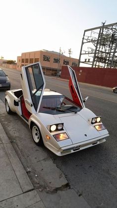 a white car with its doors open parked on the side of the road next to another car