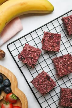 some food is sitting on a cooling rack next to bananas and strawberries, along with other foods