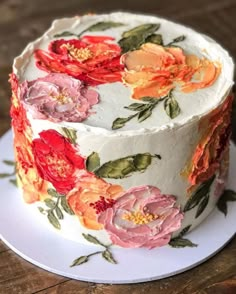 a white cake with red and orange flowers on it's icing is sitting on a plate