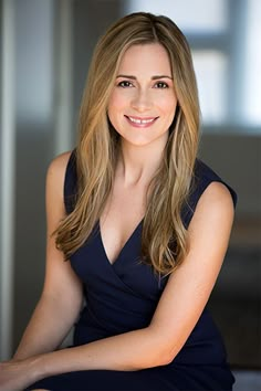 a woman in a blue dress posing for a photo with her hands on her knees