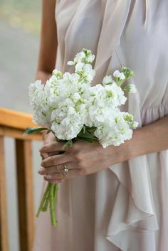 a woman in a white dress holding a bouquet of flowers