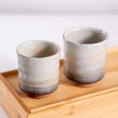 two cups sitting on top of a wooden tray