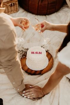 two people toasting wine glasses over a cake