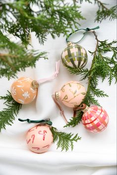 some ornaments are hanging from the branches of a christmas tree on a white tablecloth