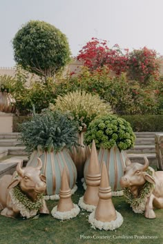 three vases with plants in them sitting on the grass near some steps and bushes