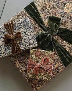 three wrapped gift boxes with bows tied on top of each other in various patterns and colors