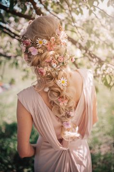 a woman standing under a tree with flowers in her hair and wearing a pink dress