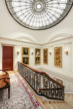 an ornate staircase leads up to the second floor with paintings on the walls and ceiling