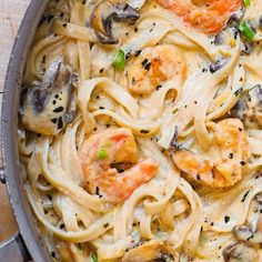 a pan filled with pasta and shrimp on top of a table