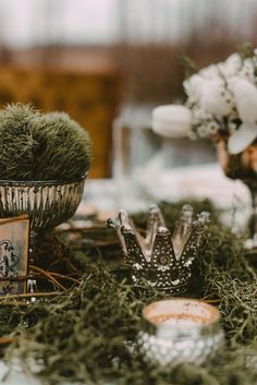 the table is covered with moss and silverware for an elegant wedding reception or bridal party