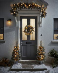 a front door decorated with christmas lights and wreaths