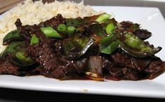 a white plate topped with meat and vegetables covered in sauce on top of gravy